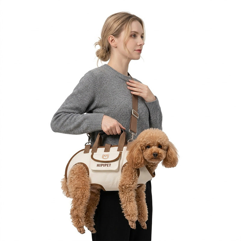 Woman carrying a small brown dog in a khaki 4-in-1 dog carrier harness with crossbody strap.