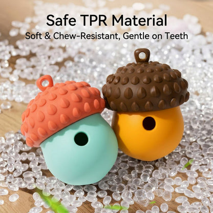 Two acorn dog treat dispenser toys in mint, coral, yellow, and brown sit on clear beads over a wooden surface.