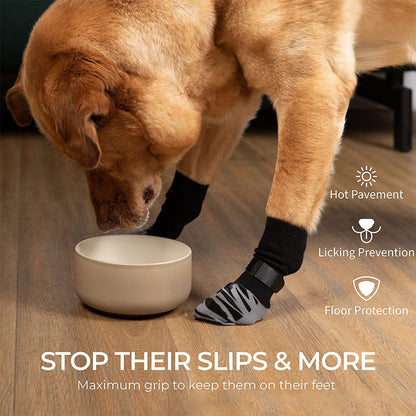 Yellow Labrador wearing anti-slip dog socks and leg warmers on a hardwood floor beside a bowl.
