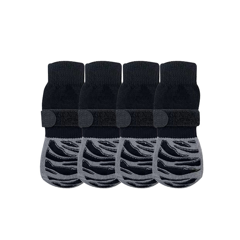 Four black anti-slip dog socks and leg warmers with rubber grips, shown on a white background.