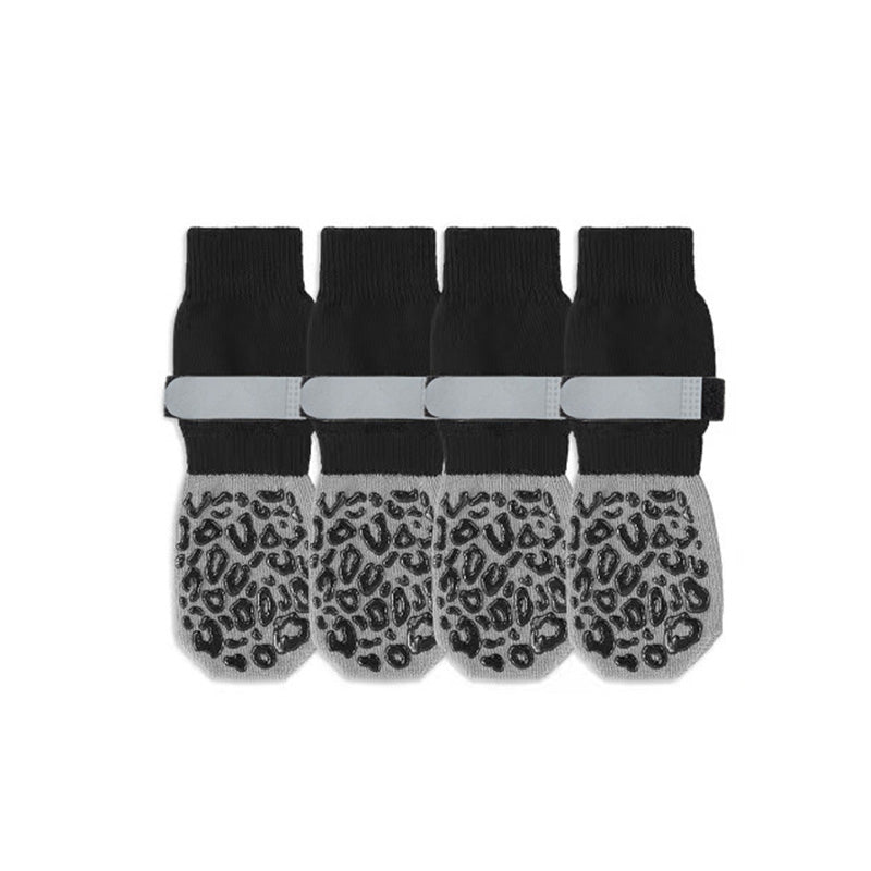 Four black and gray anti-slip dog socks with leopard-grip soles and gray straps on a white studio background.