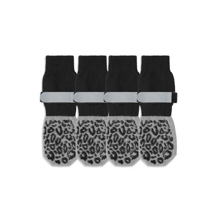 Four black and gray anti-slip dog socks with leopard-grip soles and gray straps on a white studio background.
