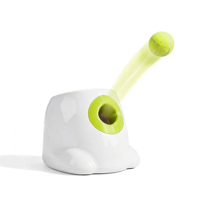 White automatic dog ball launcher with a lime green opening launching a yellow tennis ball on a white background.