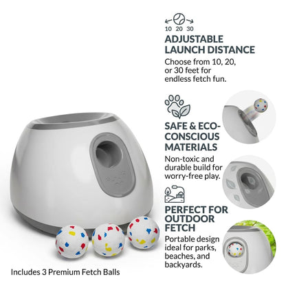 Studio shot on white background of a gray automatic dog ball launcher, three colorful fetch balls, and feature callouts.