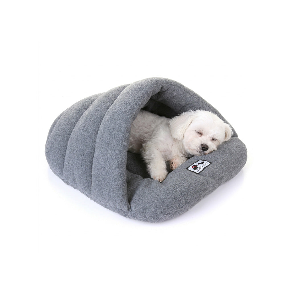 Small white dog sleeping inside a heather grey fleece cave bed with hooded sleeping-bag shape.