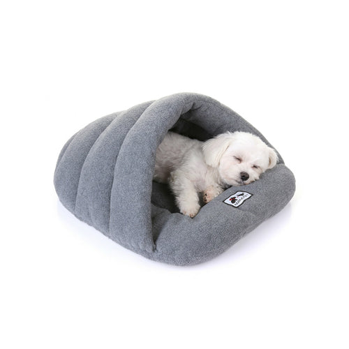 Small white dog sleeping inside a heather grey fleece cave bed with hooded sleeping-bag shape.