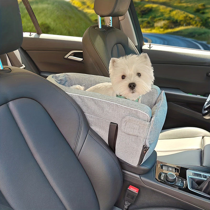 Happy small white dog enjoying a car ride while sitting safely in a center console dog car seat right next to the driver.
