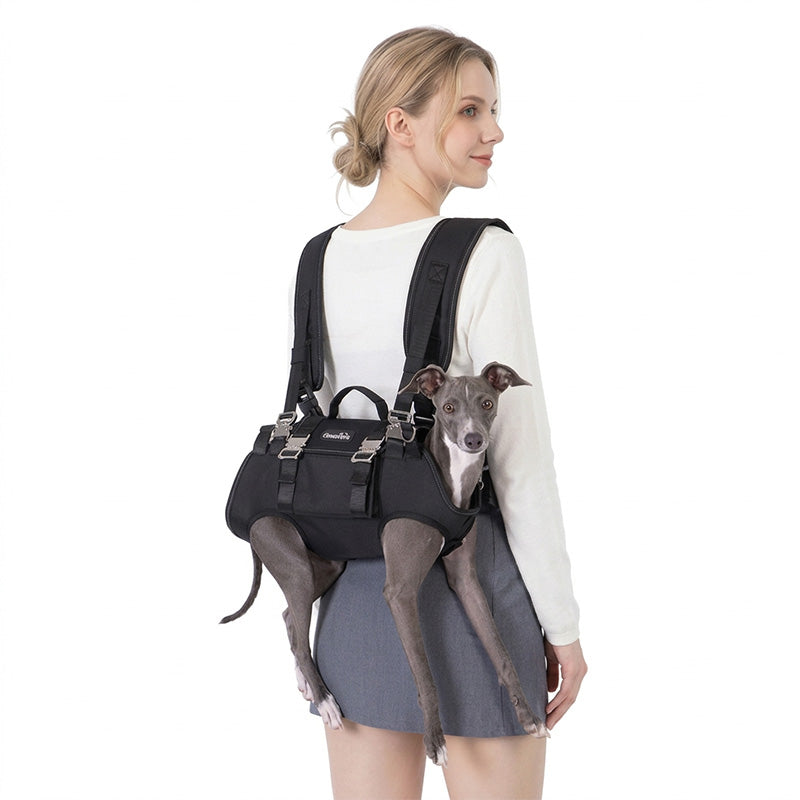 Woman wearing a black horizontal dog carrier backpack with a small grey dog supported through leg openings.