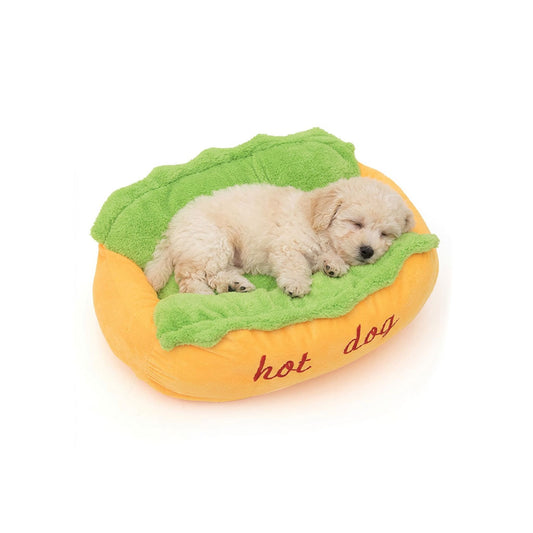 Small cream puppy sleeping in a hot dog pet bed with yellow raised rim and green cushion.