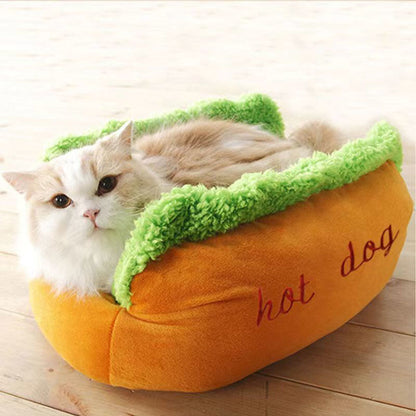 Fluffy cat resting inside the hot dog pet bed on a light wood floor.