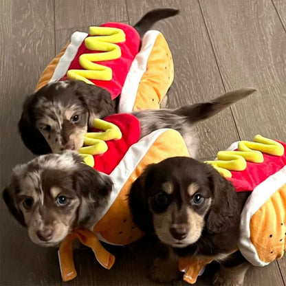 Three dachshund puppies wearing plush hot dog pet costumes on a wood floor.