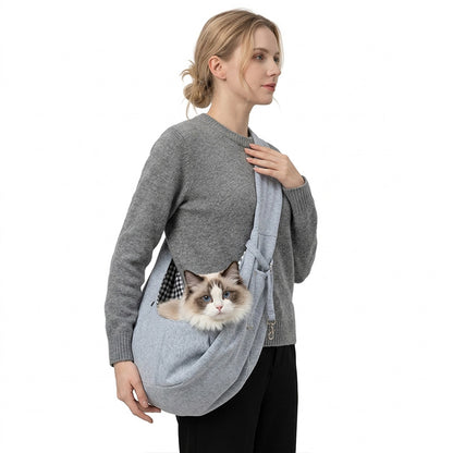Woman wearing a heather gray pet sling carrier with a fluffy cat looking out.