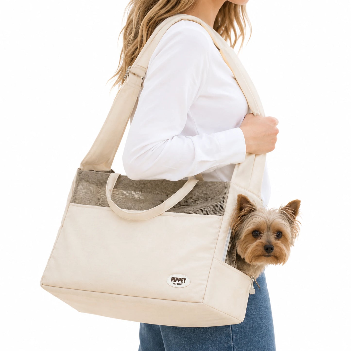 Cream canvas shoulder pet carrier worn by a woman with a Yorkshire Terrier looking out of the side opening