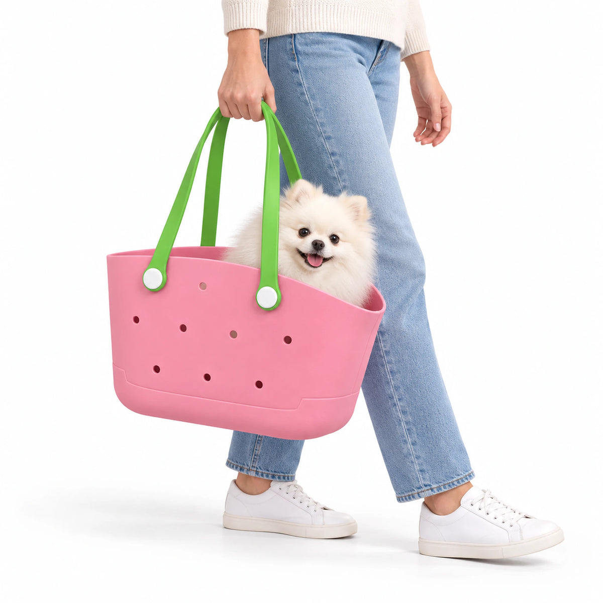 Pink pet carrier basket with green loop handles, carried by a woman with a small white dog inside