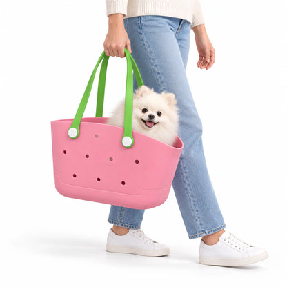 Pink pet carrier basket with green loop handles, carried by a woman with a small white dog inside