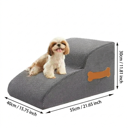 Small Shih Tzu dog sitting safely on a grey 2-step foam dog stair placed next to a living room sofa.