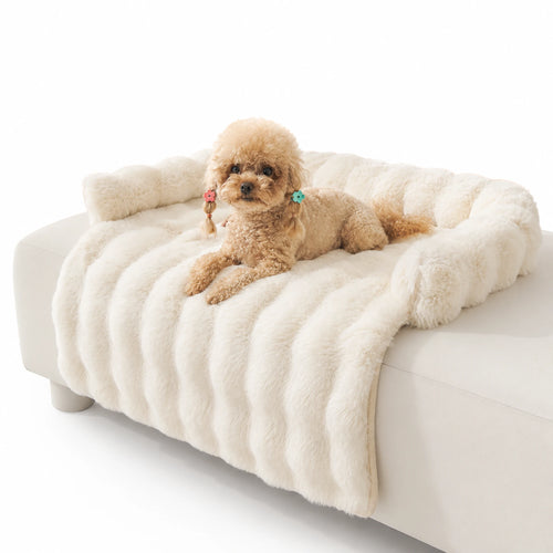 Cream long-pile faux-fur pet sofa cover with bolster on a white couch, toy poodle resting on top
