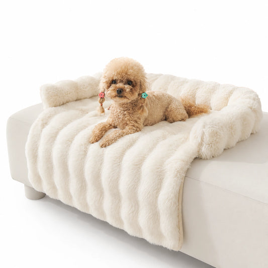 Cream long-pile faux-fur pet sofa cover with bolster on a white couch, toy poodle resting on top
