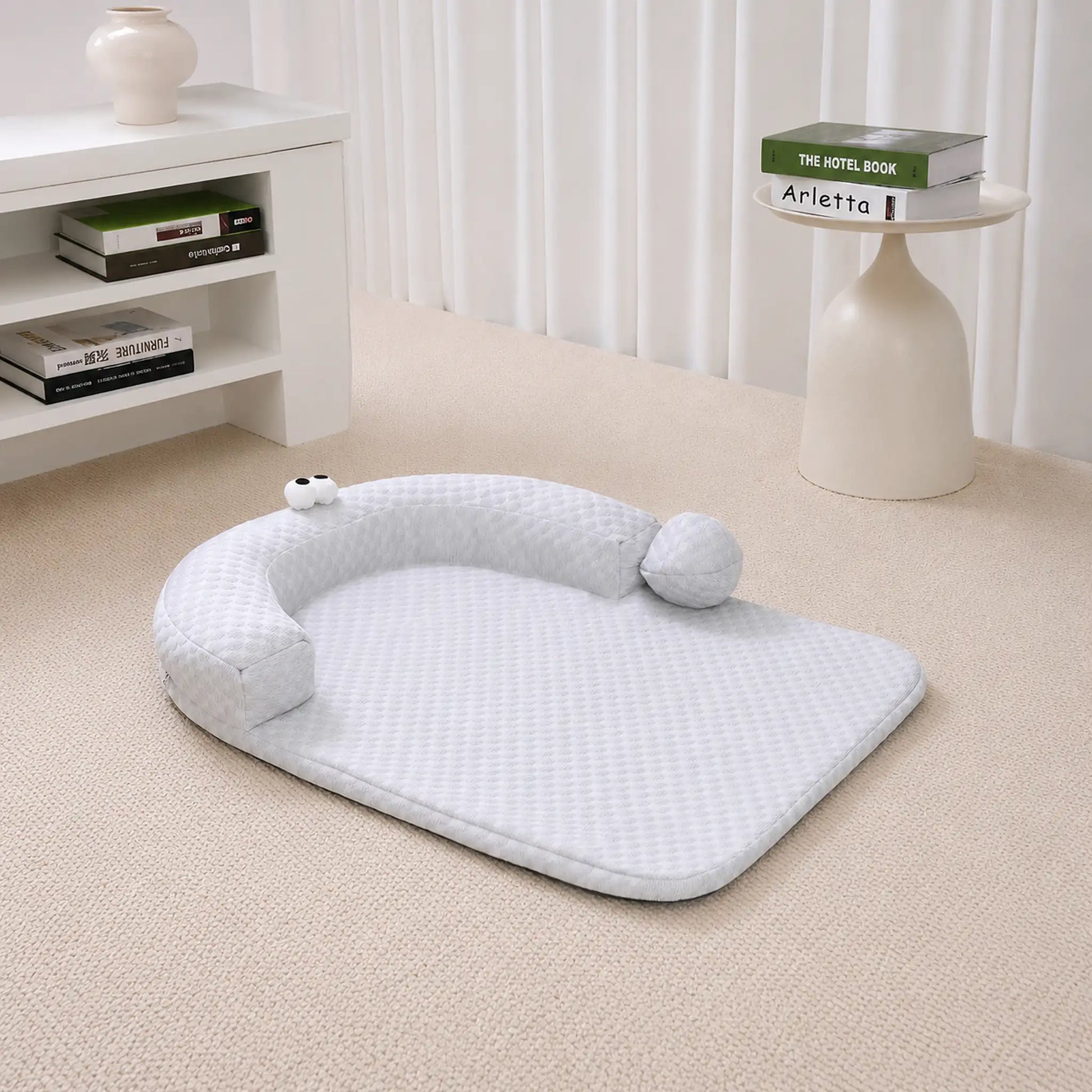 Gray ice-bead cooling pet bed with C-shaped bolster on a beige carpet