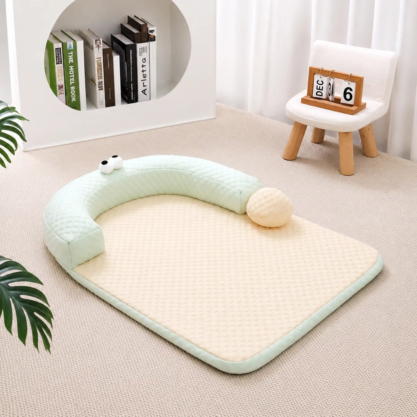 Sage-green ice-bead cooling pet bed with C-shaped bolster on a beige carpet