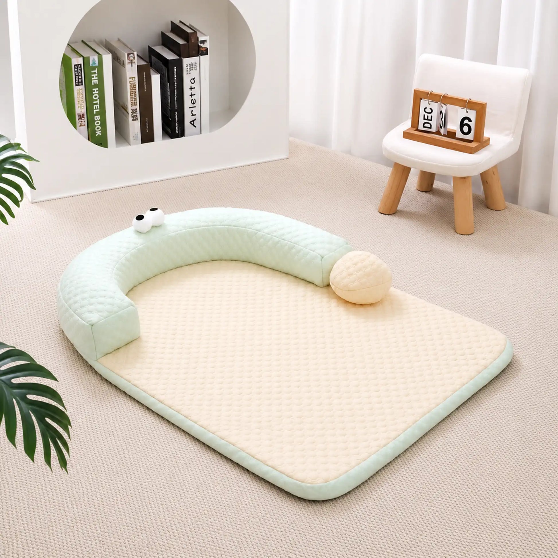 Sage-green ice-bead cooling pet bed with C-shaped bolster on a beige carpet