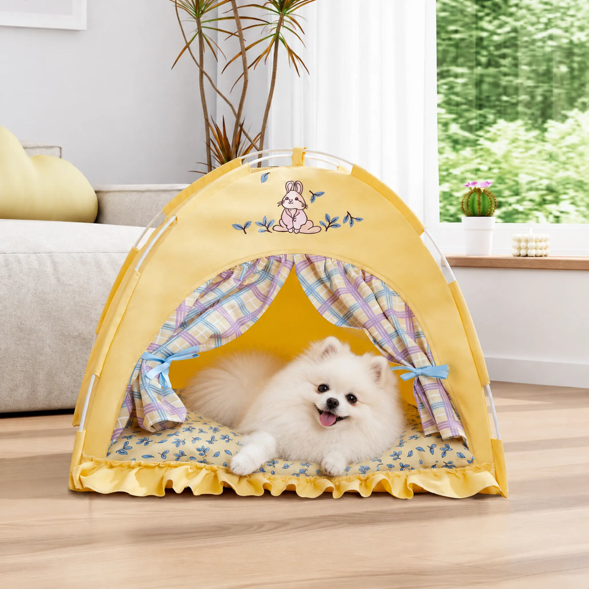 White Pomeranian lying inside a yellow bunny pet tent beside a sofa