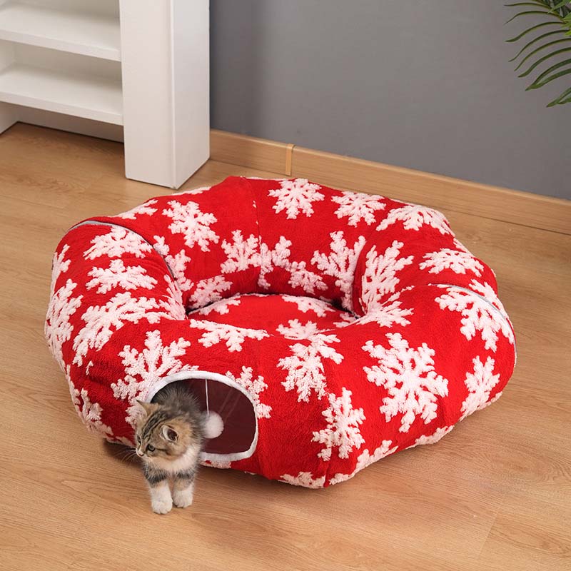 Festive Red Snowflake variant — tabby kitten peeking from the red snowflake plush donut cat tunnel bed on a wood floor.