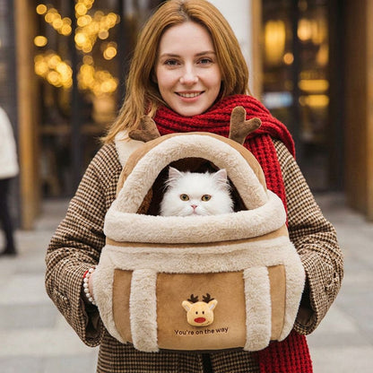 Woman outdoors wearing the plush reindeer pet carrier backpack with a white cat inside.