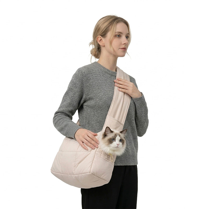 Woman carrying a Ragdoll cat in a khaki quilted winter sling carrier.