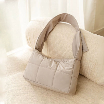 Gray quilted winter cat sling carrier product shot on a cream sofa.