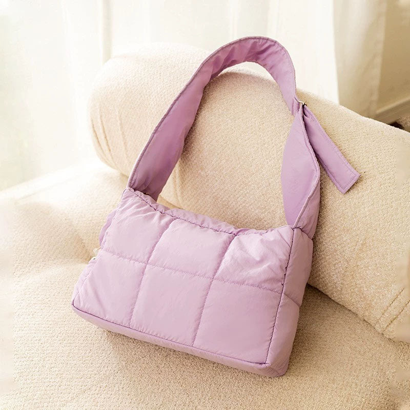 Purple quilted winter cat sling carrier product shot on a cream sofa.