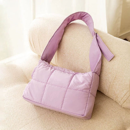 Purple quilted winter cat sling carrier product shot on a cream sofa.