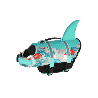 Tropical sailboat pattern dog life jacket with an aqua blue shark fin. High buoyancy dog swim vest showing adjustable buckles, breathable mesh belly, and sturdy grab handle.