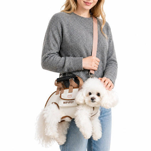 Horizontal crossbody dog carrier worn by woman with small white dog