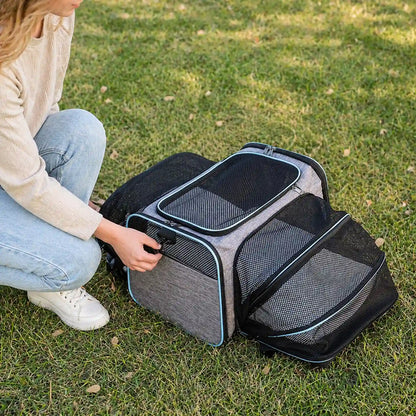 Owner kneeling beside fully expanded gray-and-blue pet carrier on grass