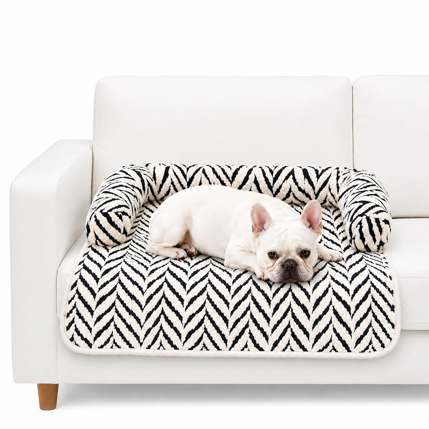 White French Bulldog resting on black and white plush sofa pet bed with raised pillow