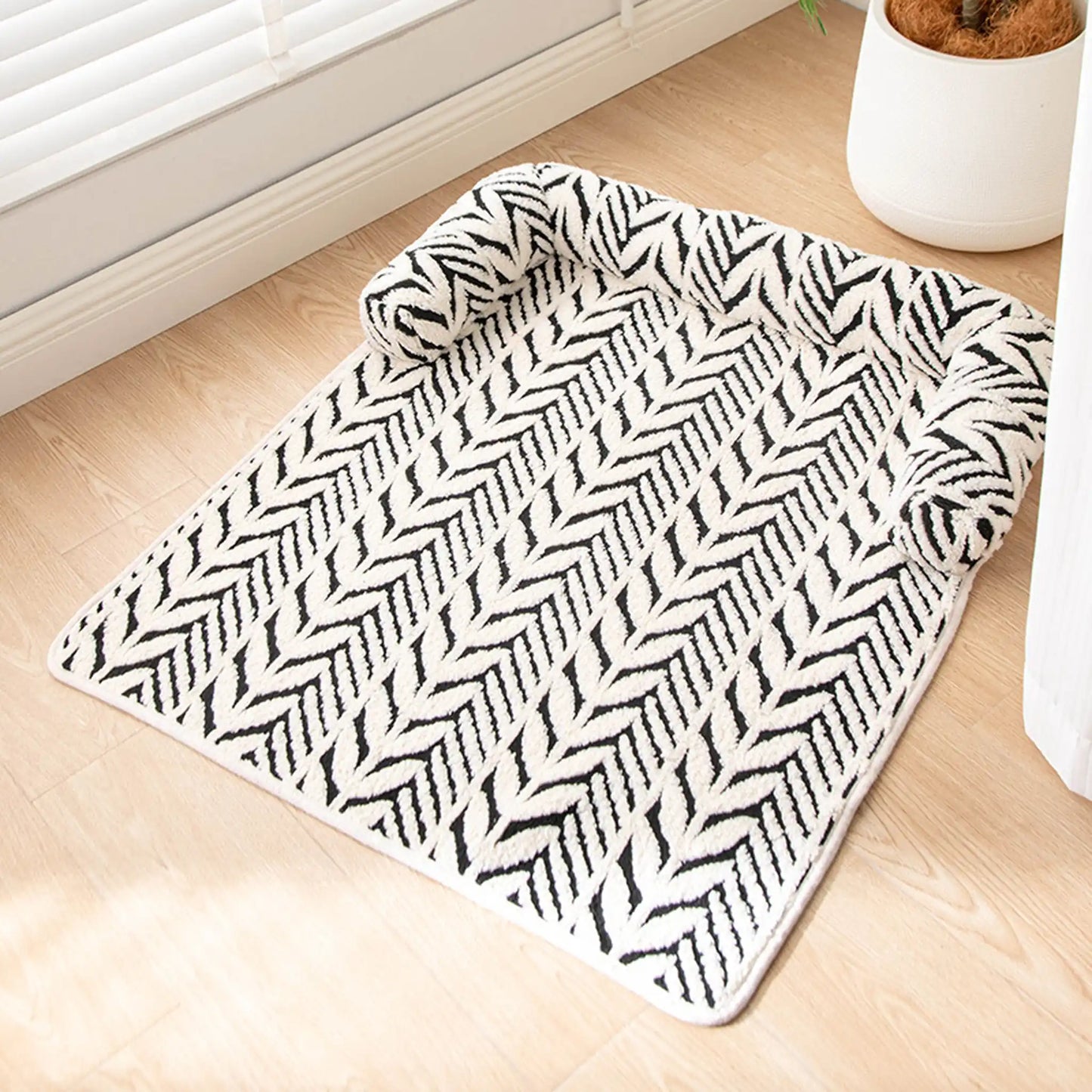 Black and white plush sofa pet bed shown on wood floor